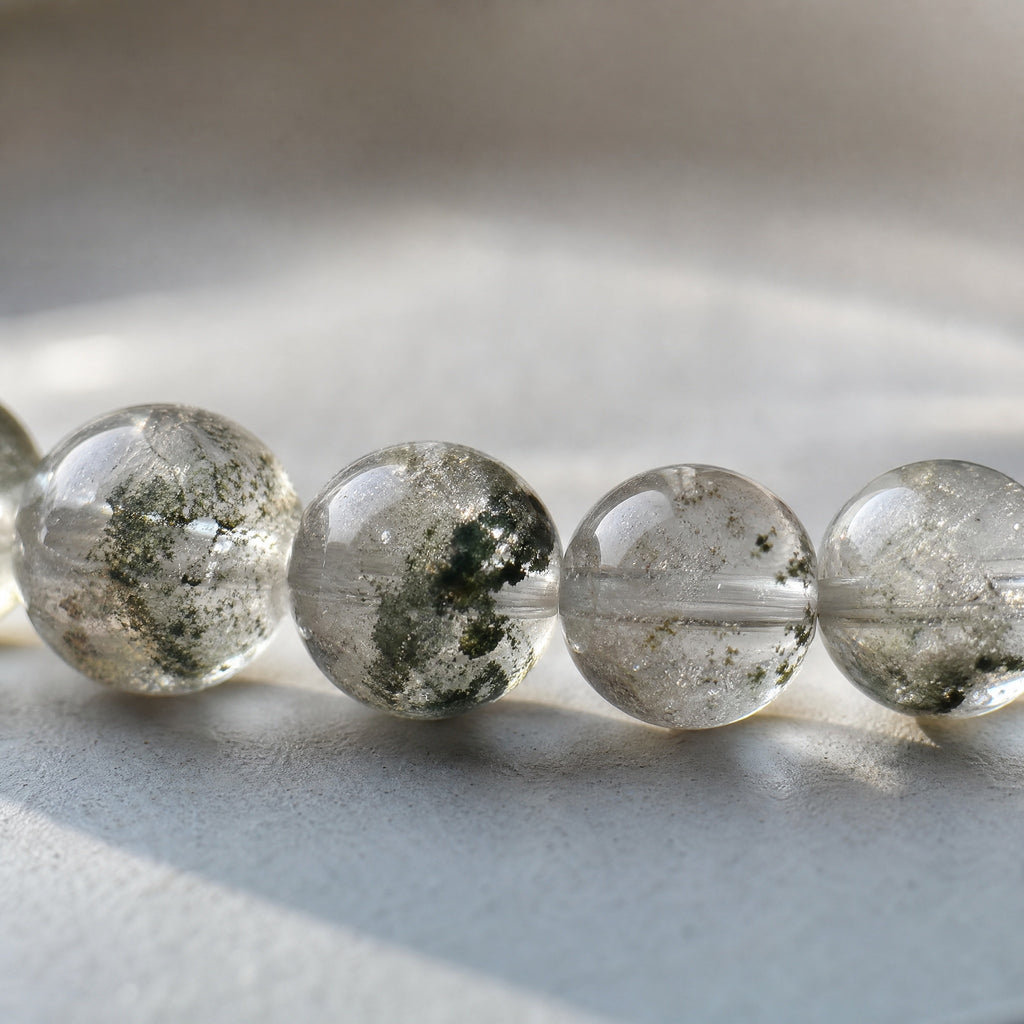 Close-up of natural Green Phantom Quartz bracelet beads with visible green mineral inclusions.